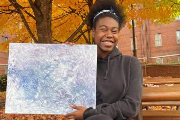 Kiara Chambers holding one of her paintings