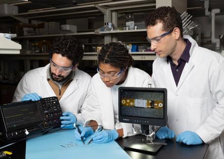 Lead study author Ramy Ghanim (left) and co-author Joy Jackson test an small implantable device alongside Assistant Professor Alex Abramson. In a new Science paper, they describe a networking system that connects therapeutic implants and wearable devices by using the body's natural conductivity to send tiny signals.
