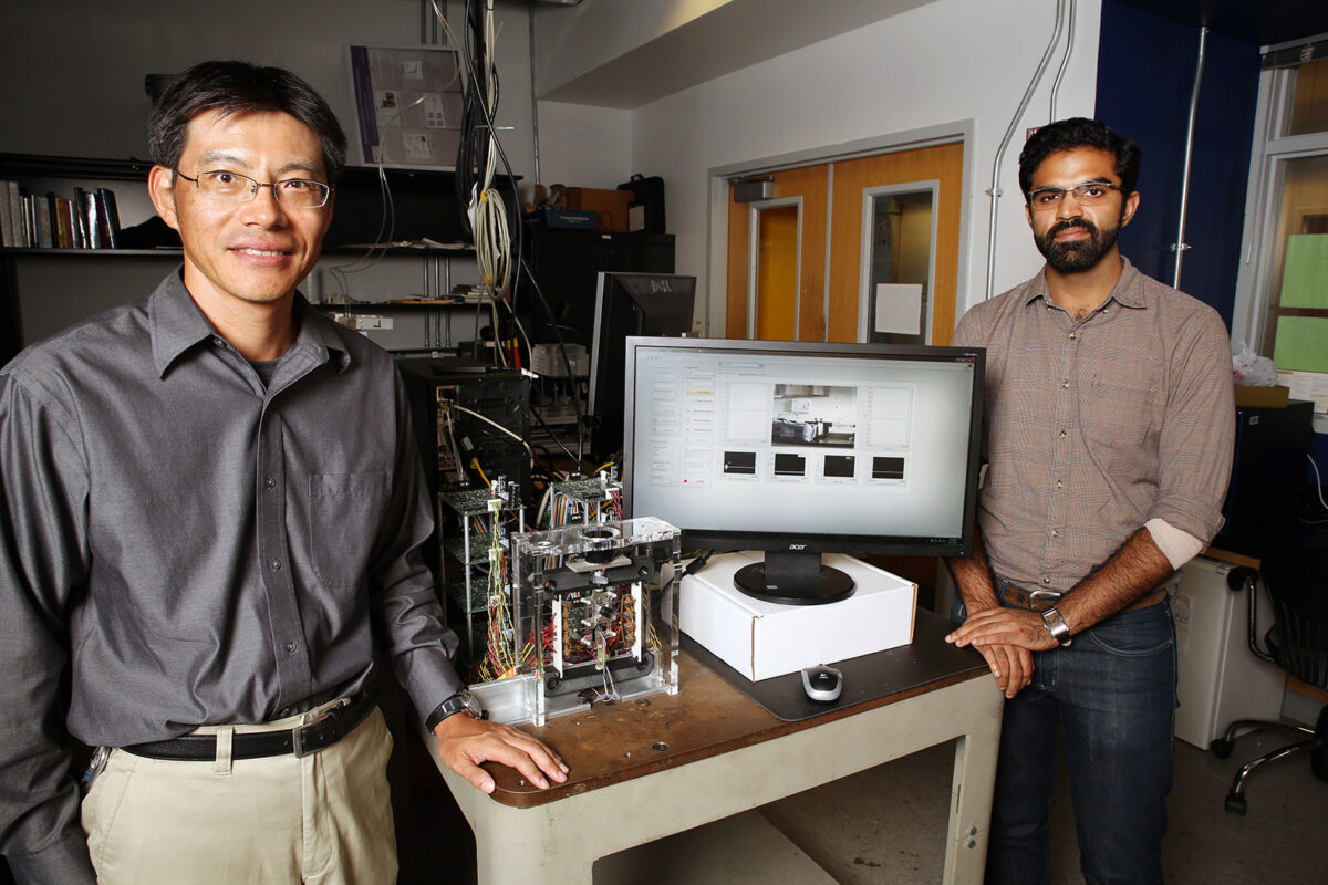 Dr. Ueda standing by table that displays research project